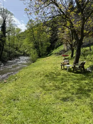 two benches sitting in the grass next to a river at Vikendica Borjak in Kraljevo