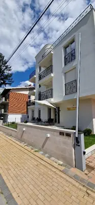 a white building on a street next to a sidewalk at Apartman Vera in Vrnjačka Banja