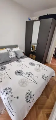 a bed with a black and white blanket with dandelions on it at Apartman Vera in Vrnjačka Banja