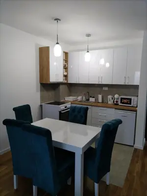 a kitchen with a white table and blue chairs at Apartman TRI PRINCEZE in Soko Banja