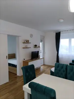 a living room with a table and chairs and a television at Apartman TRI PRINCEZE in Soko Banja