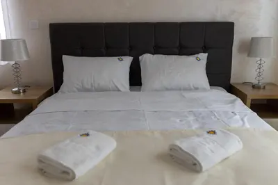 a bed with two towels on it with two lamps at Apartman Sunce Lux A in Vrnjačka Banja