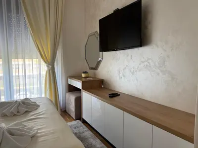 a bedroom with a desk with a television on the wall at Apartman Sunce Lux A in Vrnjačka Banja