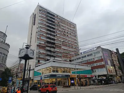 a tall building with a clock in front of it at Plan B in Niš