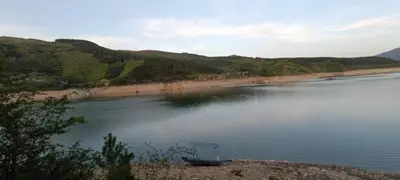a boat sitting on the water next to a beach at Vila Piramida - Zavojsko jezero-Pirot in Bukorovac