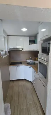 a kitchen with white cabinets and a wooden floor at Vila Piramida - Zavojsko jezero-Pirot in Bukorovac