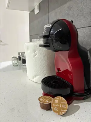 a red coffee maker sitting on a kitchen counter with coins at Apartman Kostić in Niš