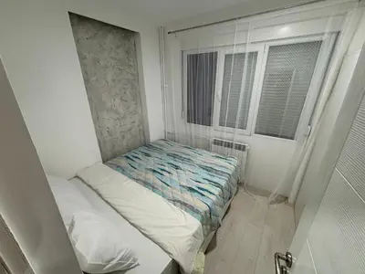 a small bed in a small room with a window at Apartman Kostić in Niš