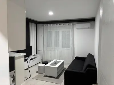 a living room with a black couch and a tv at Apartman Kostić in Niš
