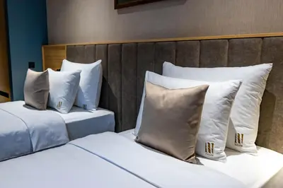two beds with white pillows sitting next to each other at Hotel Helm in Niš