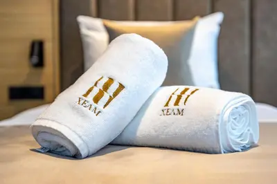 two rolled towels sitting on top of a bed at Hotel Helm in Niš