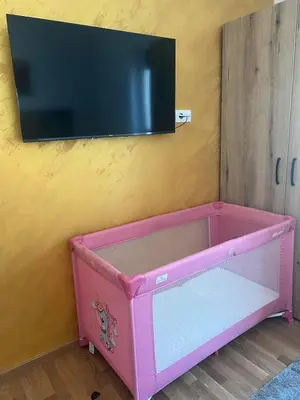 a pink dresser with a tv on a wall at Toplina Doma Sokobanja in Soko Banja