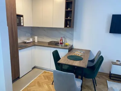 a small kitchen with a wooden table and chairs at Apartman MM Vrnjacka Banja in Vrnjci