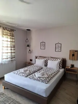a bedroom with a large bed with white sheets at Guest House Dimitrije in Niška Banja