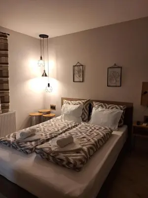 a bedroom with a large bed with white sheets and pillows at Guest House Dimitrije in Niška Banja