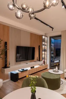 a living room with a large television and green chairs at Planet Residence NiNa in Niš