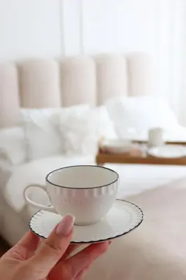 a person holding a cup on a plate at Banja Maison in Vrnjačka Banja