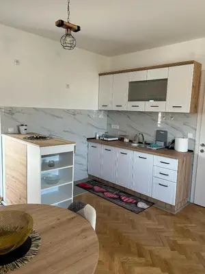 a kitchen with white cabinets and a wooden table at Apartman Stević in Vrnjci