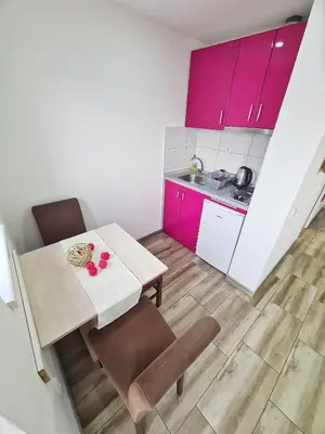 a small kitchen with pink cabinets and a table and chairs at Vila Aleksandra 2 Studio 9 in Soko Banja