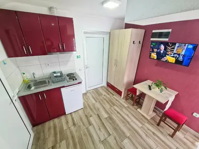 a small kitchen with red cabinets and a table at Vila Aleksandra 2 Studio 16 in Soko Banja
