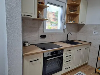 a kitchen with white cabinets and a sink and a window at MIL apartment Sokobanja in Soko Banja