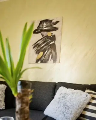 a painting of a woman wearing a hat on a couch at Apartman Korićanac I Vrnjačka Banja in Vrnjačka Banja