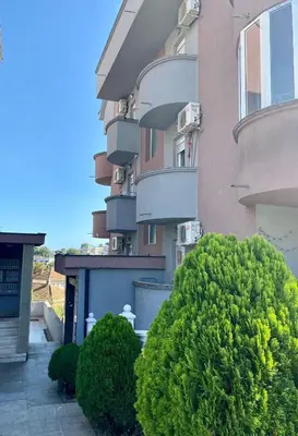 a building with green bushes in front of it at Apartman Đalić in Vrnjačka Banja