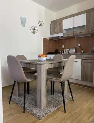 a kitchen with a table with chairs and a bowl of fruit on it at Apartman Đalić in Vrnjačka Banja