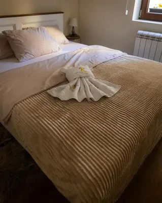 a white bed with a towel on the end of it at Apartman Korićanac II Vrnjačka Banja in Vrnjačka Banja