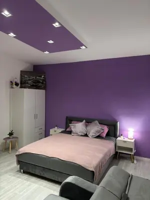 a purple bedroom with a bed and a couch at Apartman LILLY in Paraćin
