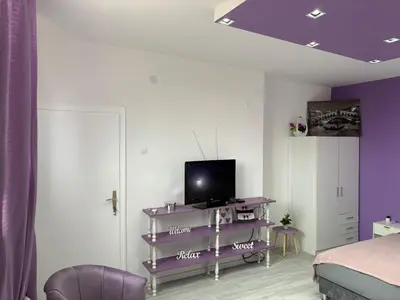 a bedroom with a bed and a tv on a purple shelf at Apartman LILLY in Paraćin