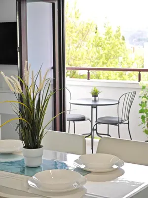a table with white plates and chairs on a balcony at Apartmani Čokić Sokobanja in Soko Banja