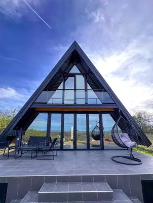 a house with a triangular roof with glass windows at Kod Lutajuceg in Despotovac