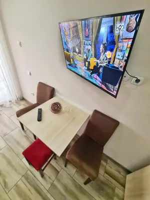 a table with chairs and a tv hanging on a wall at Vila Aleksandra 2 Studio 13 in Soko Banja