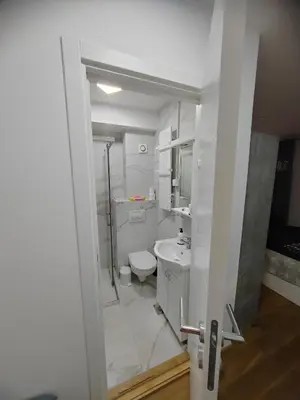a white bathroom with a toilet and a sink at OgiApartman in Vrnjačka Banja