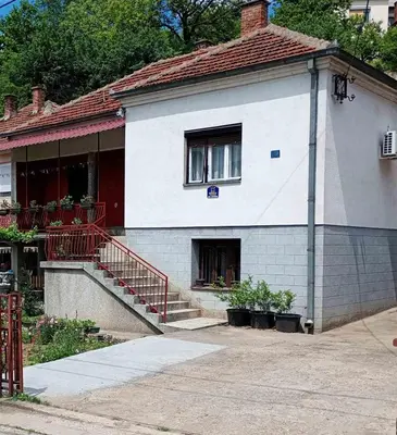 a white house with a red staircase in front of it at BoHan sobe Vladičin Han in Vladičin Han