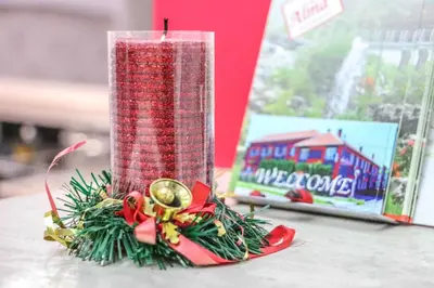 a red christmas candle on a table next to a box at Garni hotel Alma in Pirot