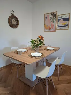 a dining room table with chairs and a clock on the wall at Nikana in Vrnjačka Banja