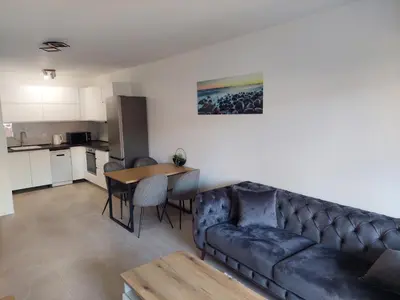 a living room with a couch and a table and a kitchen at Brand new apartment in the city center in Niš