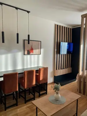 a dining room with a table and chairs and a tv at NLux Nest Milmari in Kopaonik
