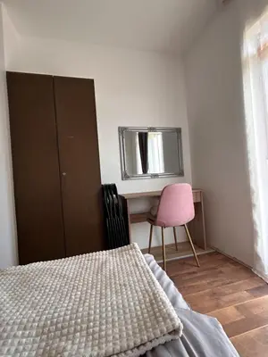a bedroom with a bed and a desk with a pink chair at Apartmani Dana in Vranje