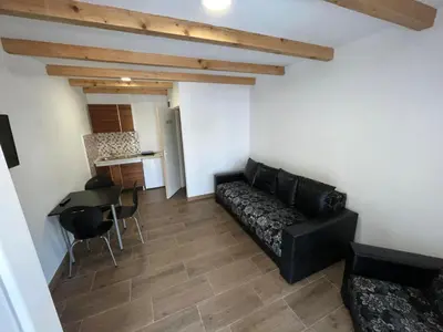 a living room with a black couch and a kitchen at Studio in Soko Banja