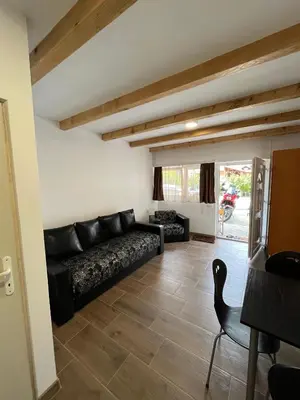a living room with a black couch and a chair at Studio in Soko Banja