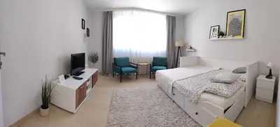 a bedroom with a bed and a desk and a tv at SQUARE apartment in Ćuprija