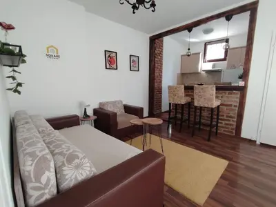 a living room with a couch and a kitchen at SQUARE apartment in Ćuprija