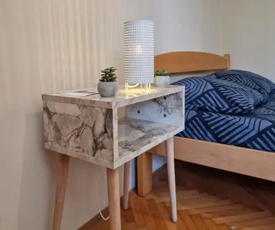 a table with two plants on it next to a bed at Apartmani Central Vrnjačka Banja Šetalište in Vrnjačka Banja