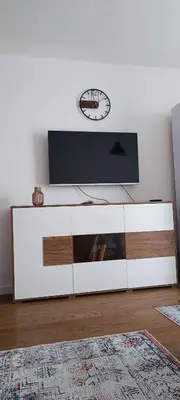 a white entertainment center with a clock on a wall at Planet-A1012 in Niš