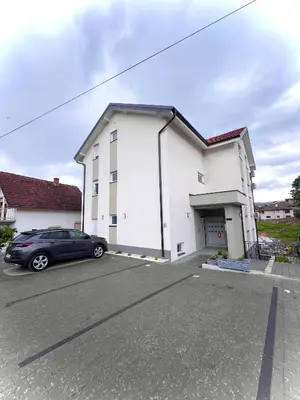a white building with a car parked in a parking lot at Banjski Raj in Vrnjačka Banja