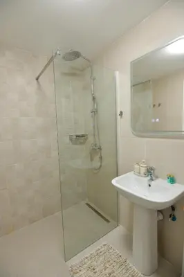 a bathroom with a glass shower and a sink at Amazon Royale Apartment in Niš