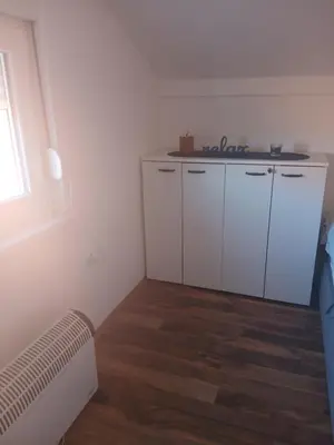 a room with white cabinets and a wooden floor at Bufan apartman in Soko Banja